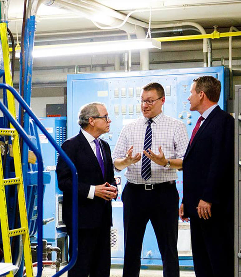 Governor Mike DeWine and Lt. Governor Jon Husted speaking with business leader in manufacturing facility.