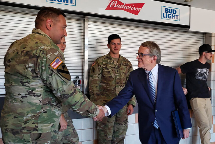 Governor Mike DeWine shaking hands with military veteran as veterans look on.